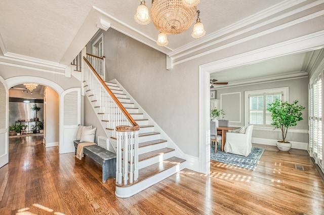 stairway featuring hardwood / wood-style flooring, crown molding, and a notable chandelier