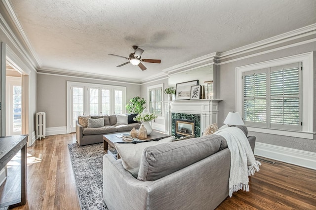 living room with crown molding, radiator, hardwood / wood-style floors, and a fireplace