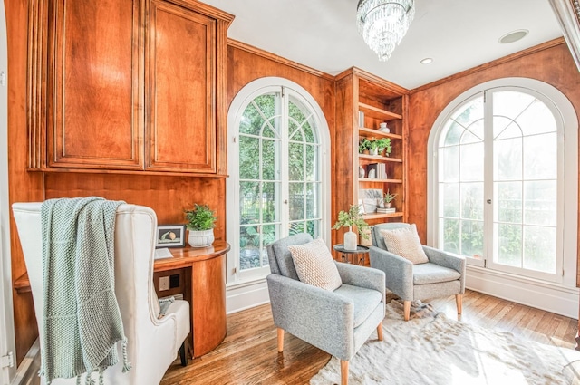 living area featuring a healthy amount of sunlight, wood-type flooring, built in features, and a chandelier