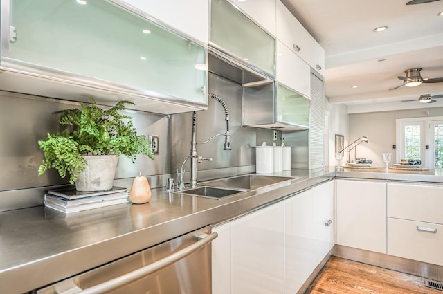 kitchen featuring white cabinetry, sink, stainless steel counters, stainless steel dishwasher, and ceiling fan