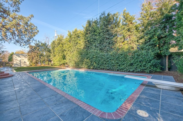 view of swimming pool with a patio and a diving board