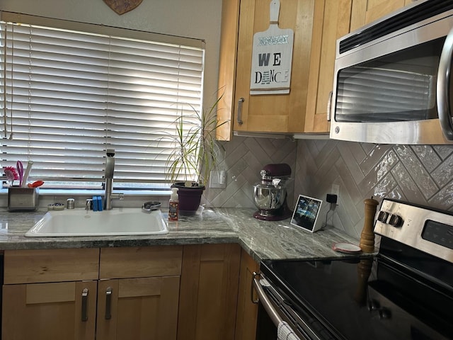 kitchen featuring tasteful backsplash, sink, stainless steel appliances, and dark stone counters