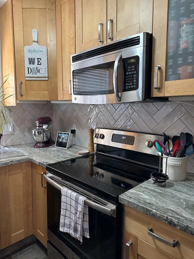 kitchen featuring stainless steel appliances, light stone countertops, and backsplash