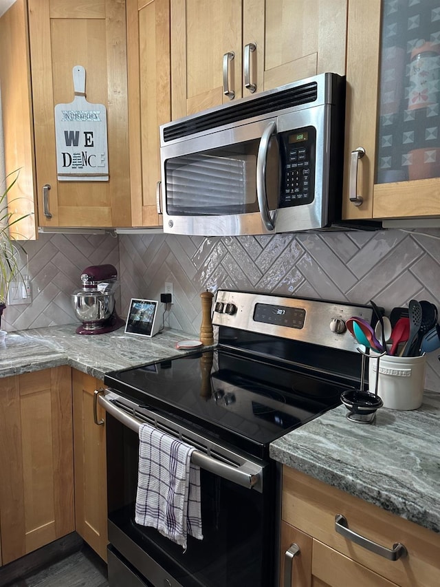 kitchen featuring brown cabinetry, tasteful backsplash, stainless steel appliances, and stone counters