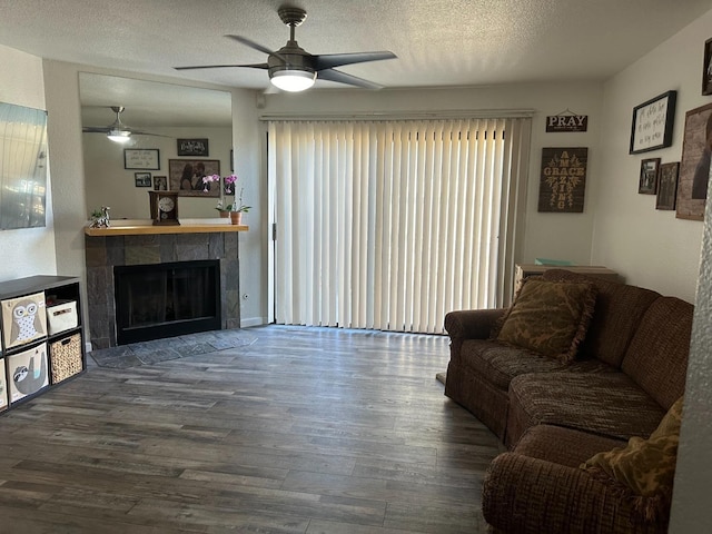 living room with a healthy amount of sunlight, hardwood / wood-style flooring, a tile fireplace, and a textured ceiling