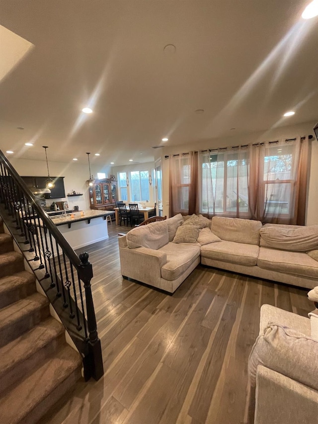 living area featuring recessed lighting, dark wood-style flooring, and stairs