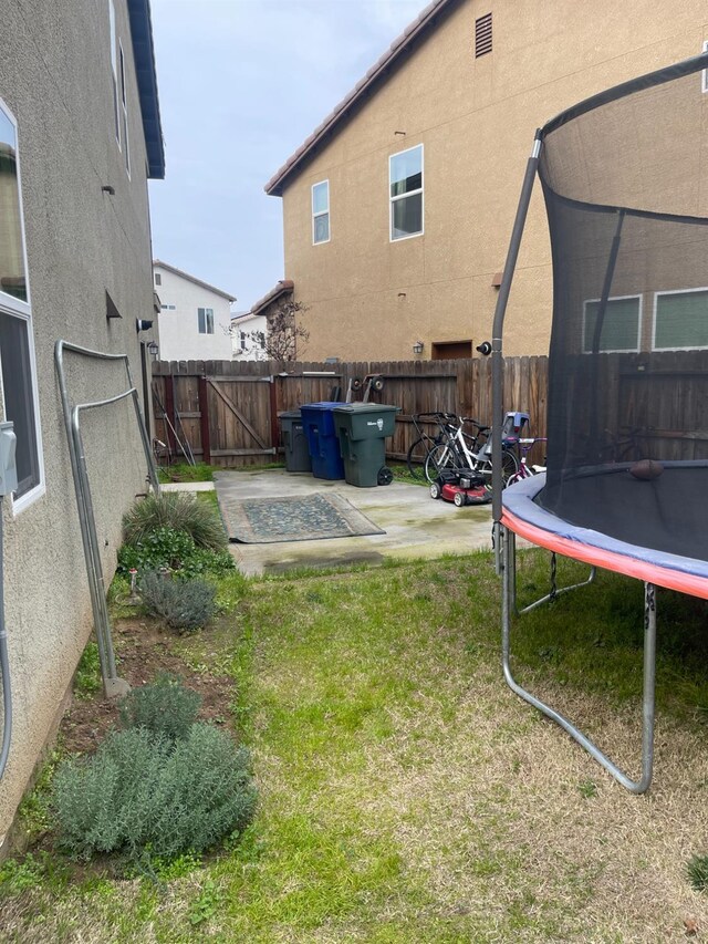 view of yard featuring a trampoline and a patio area