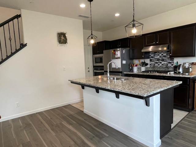 kitchen featuring hanging light fixtures, stainless steel appliances, sink, and a center island with sink