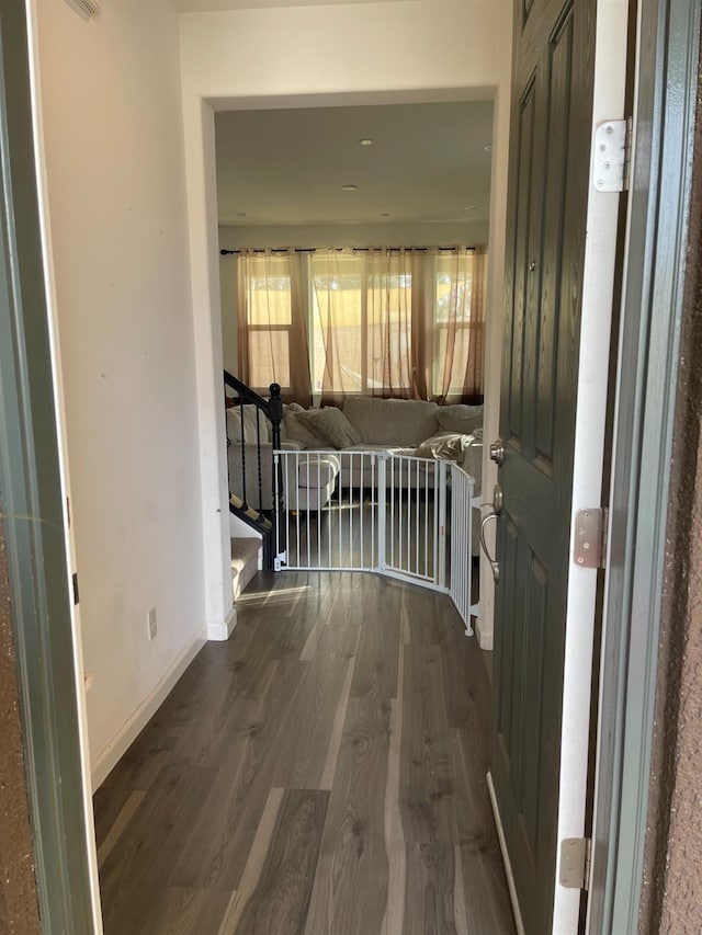 hall featuring stairs, baseboards, and dark wood-style flooring