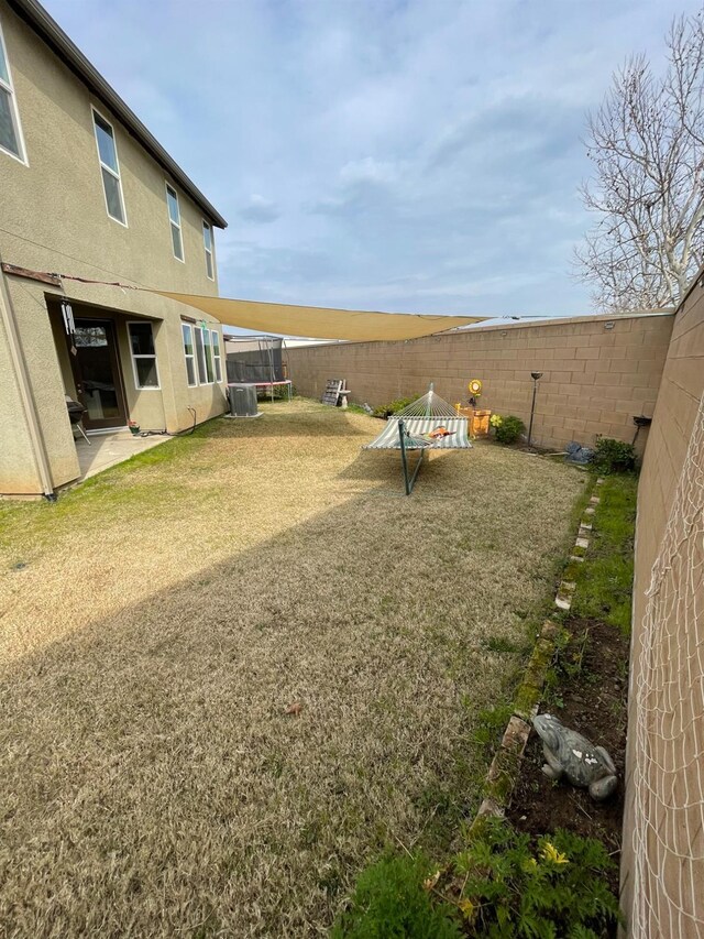 view of yard with central AC unit, a trampoline, and a patio area