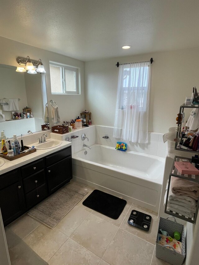 bathroom featuring a tub to relax in, tile patterned flooring, vanity, and a textured ceiling