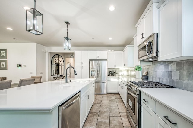 kitchen with sink, decorative light fixtures, a center island with sink, appliances with stainless steel finishes, and white cabinets