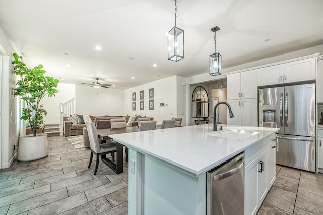 kitchen featuring sink, stainless steel appliances, white cabinets, and a center island with sink