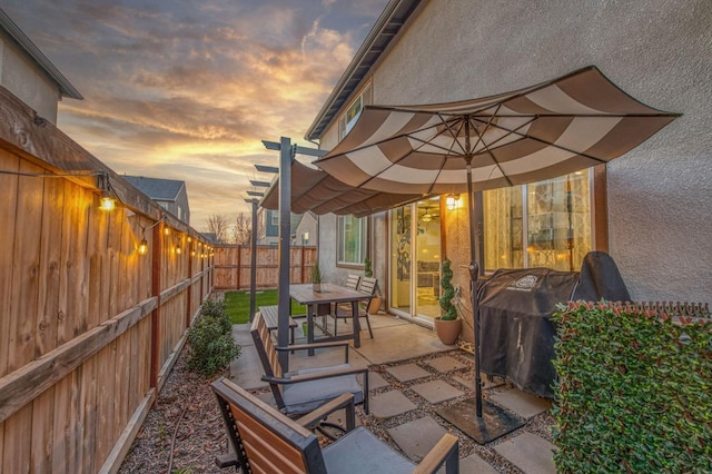 patio terrace at dusk with area for grilling and a pergola