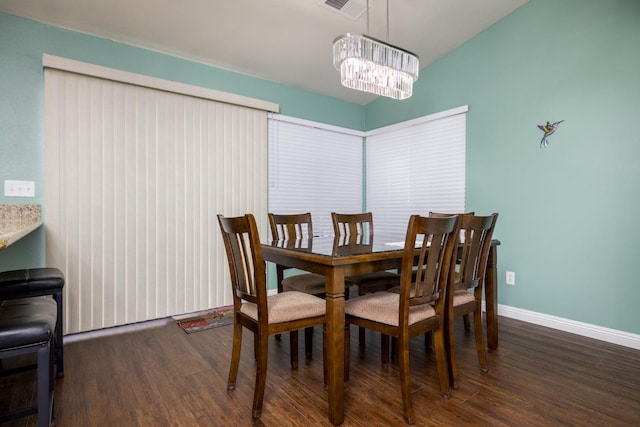 dining space featuring dark wood-type flooring and an inviting chandelier