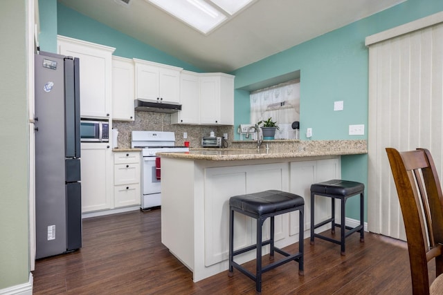 kitchen with stainless steel appliances, vaulted ceiling, white cabinetry, and kitchen peninsula