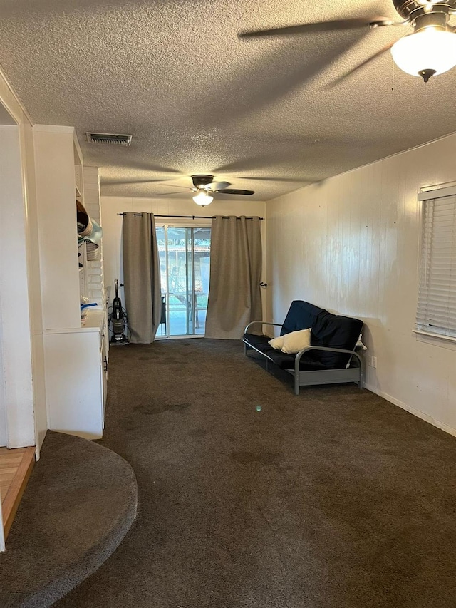 living area featuring dark colored carpet, a textured ceiling, and ceiling fan