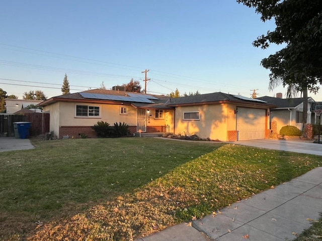 single story home featuring a garage, a front yard, and solar panels