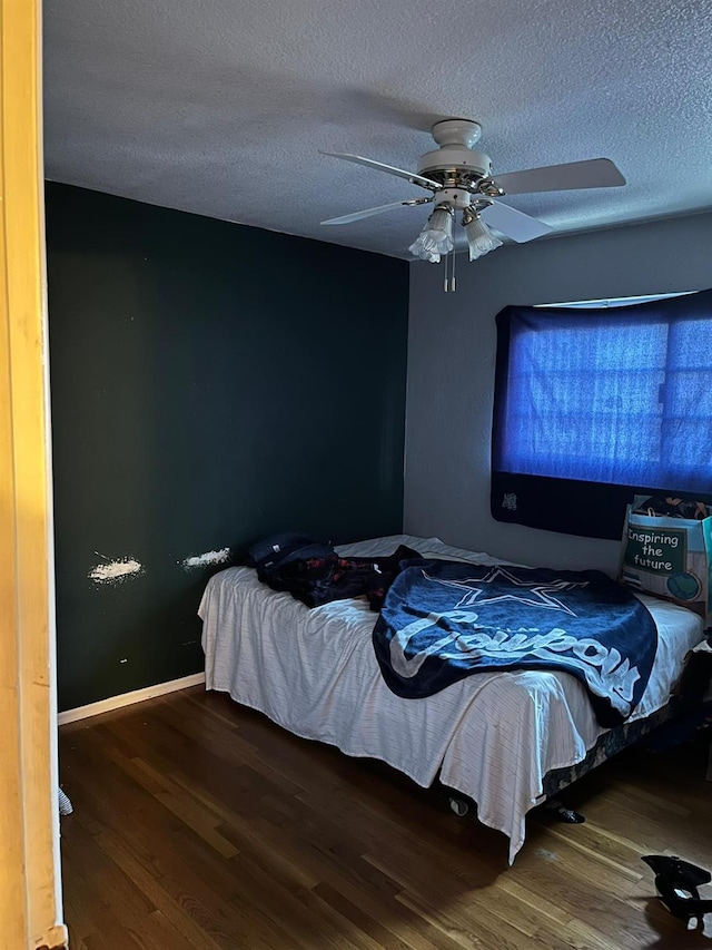 bedroom with ceiling fan, dark wood-type flooring, and a textured ceiling