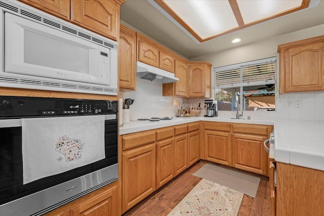 kitchen with tasteful backsplash, tile countertops, white appliances, and light hardwood / wood-style floors