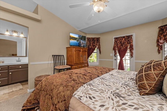 bedroom with vaulted ceiling, sink, ensuite bathroom, and ceiling fan