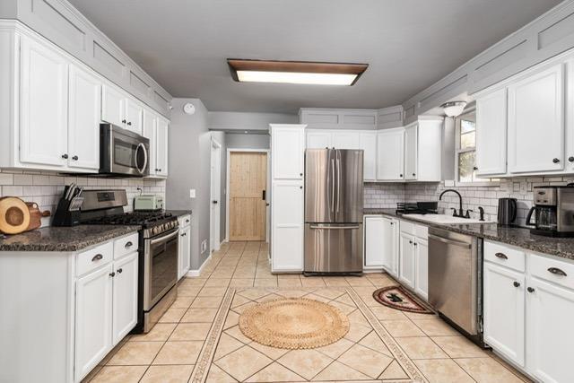 kitchen featuring light tile patterned flooring, white cabinetry, appliances with stainless steel finishes, and sink