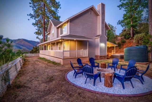 rear view of property featuring a hot tub, a mountain view, and an outdoor fire pit