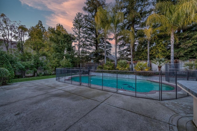 pool at dusk featuring a patio