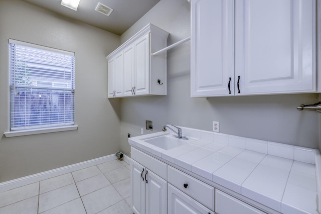 clothes washing area featuring sink, cabinets, washer hookup, light tile patterned floors, and electric dryer hookup