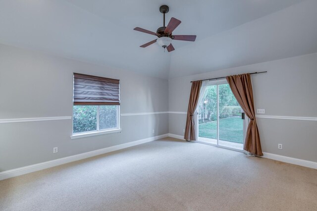 empty room featuring vaulted ceiling, light colored carpet, and ceiling fan