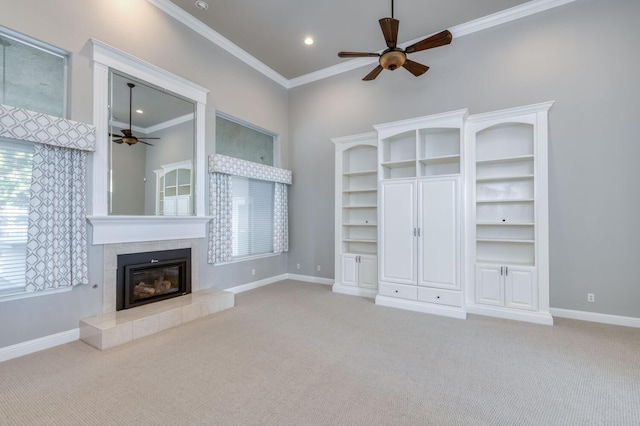 unfurnished living room with ornamental molding, carpet floors, ceiling fan, and a fireplace