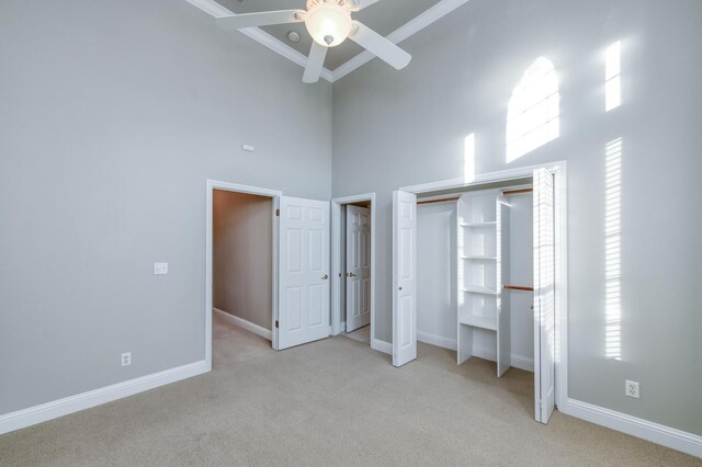 unfurnished bedroom featuring light carpet, ornamental molding, ceiling fan, and a high ceiling