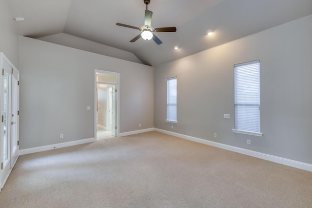 carpeted spare room featuring vaulted ceiling and ceiling fan