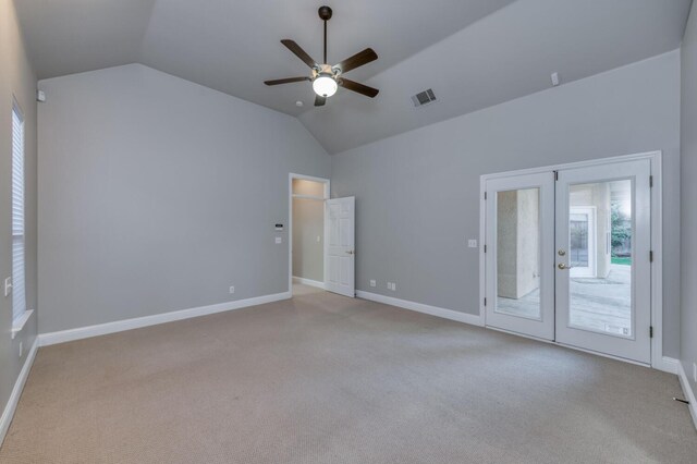 spare room featuring vaulted ceiling, light carpet, and french doors