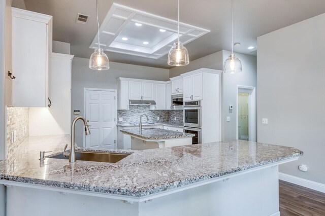 kitchen featuring white cabinetry, sink, decorative light fixtures, and stainless steel double oven