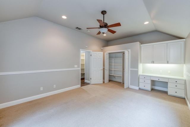 unfurnished bedroom featuring ceiling fan, light colored carpet, lofted ceiling, and built in desk