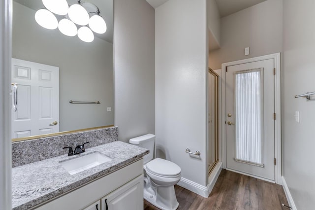 bathroom with an enclosed shower, hardwood / wood-style floors, vanity, and toilet