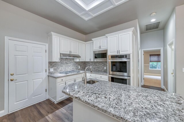 kitchen with stainless steel appliances, white cabinetry, light stone countertops, and sink