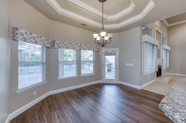 interior space with dark hardwood / wood-style floors, a notable chandelier, a fireplace, ornamental molding, and a raised ceiling