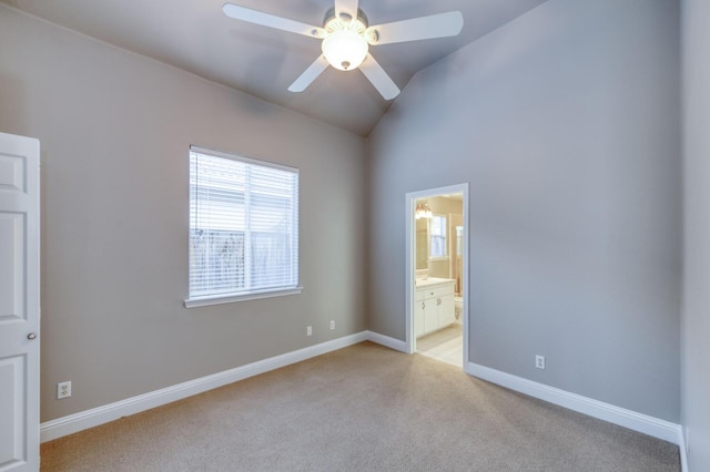 unfurnished bedroom featuring ceiling fan, ensuite bathroom, vaulted ceiling, and light carpet