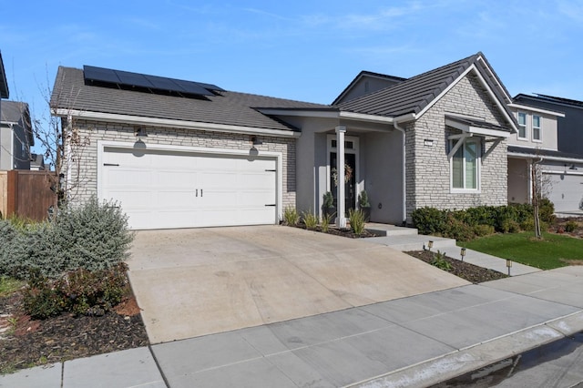 single story home with a garage and solar panels