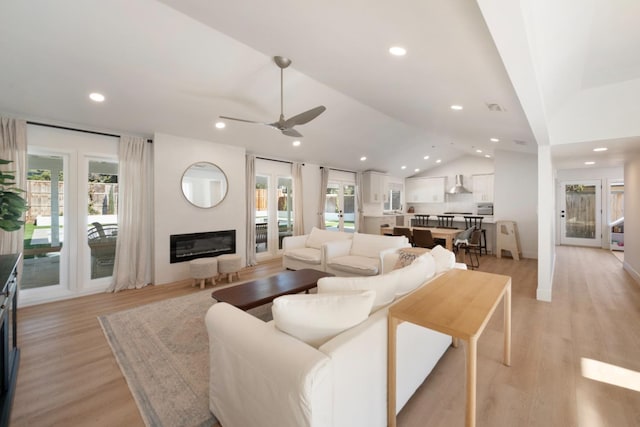 living room with french doors, ceiling fan, light hardwood / wood-style floors, and vaulted ceiling