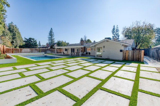 rear view of house featuring a fenced in pool and a patio area