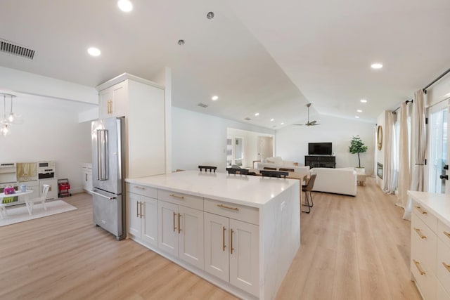 kitchen featuring vaulted ceiling, high end fridge, white cabinets, and light hardwood / wood-style floors