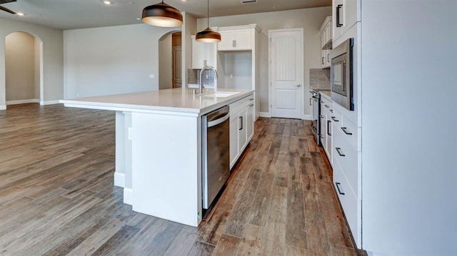 kitchen with pendant lighting, sink, a kitchen island with sink, stainless steel appliances, and white cabinets