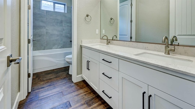 full bathroom featuring tiled shower / bath combo, wood-type flooring, vanity, and toilet