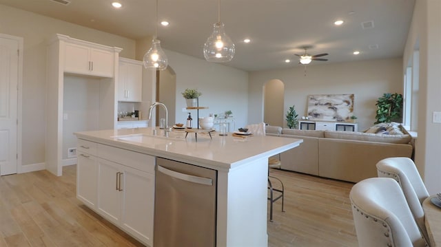 kitchen with an island with sink, sink, stainless steel dishwasher, and white cabinets