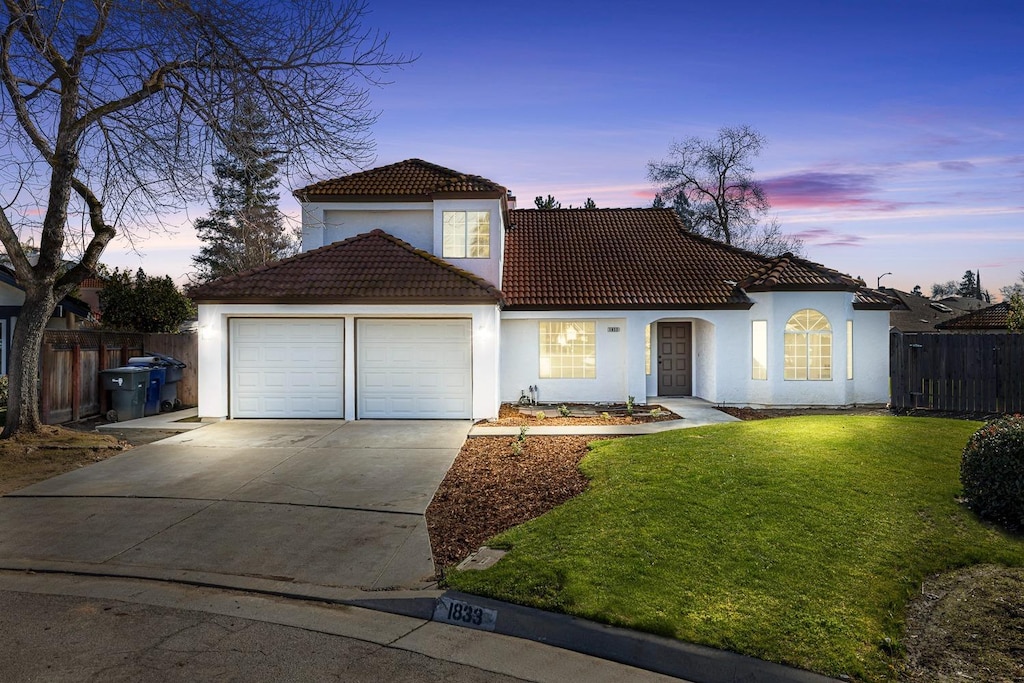 mediterranean / spanish-style house featuring a garage and a lawn