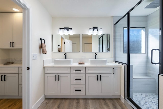 bathroom with hardwood / wood-style flooring, a shower with shower door, and vanity