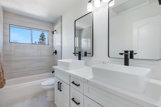 full bathroom with toilet, a textured ceiling, vanity, and tiled shower / bath